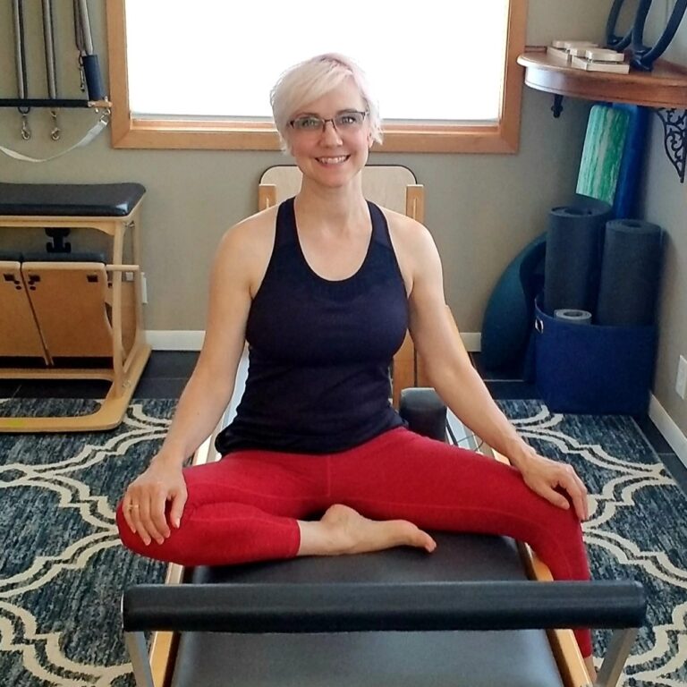 Ginny Massie sitting on Pilates Reformer