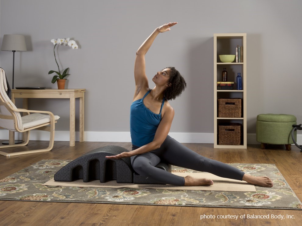 beyond the basics pilates education - woman sitting on arc barrel